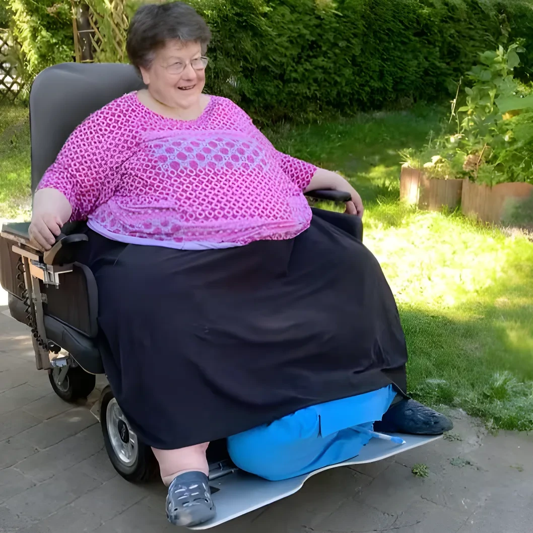 Eine Frau, die mit dem LEOplus in einem Park fährt. Bei diesem Sonderbau gibt es eine breitere Fläche für Sitz- und Rückenpolster, sowie ein breiteres Fußbrett.